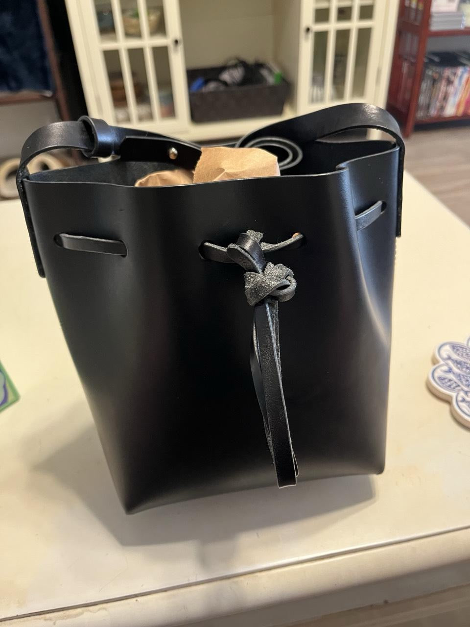 Black leather handbag bucketbag with decorative clasp on a light surface