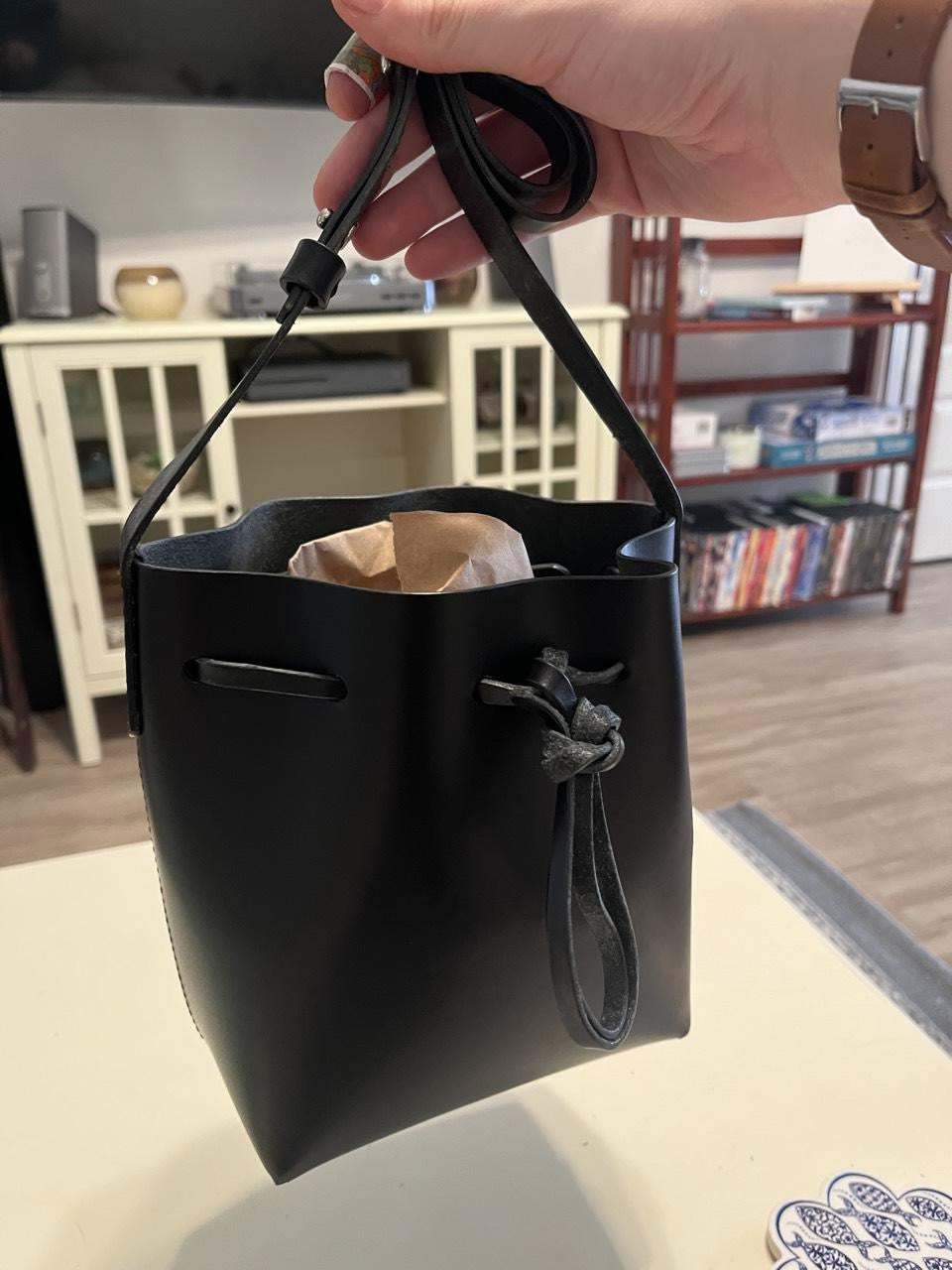 Black leather bucket bag held by hand